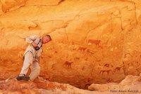 Professor Kröpelin klettert an einem Felsen mit Malereien