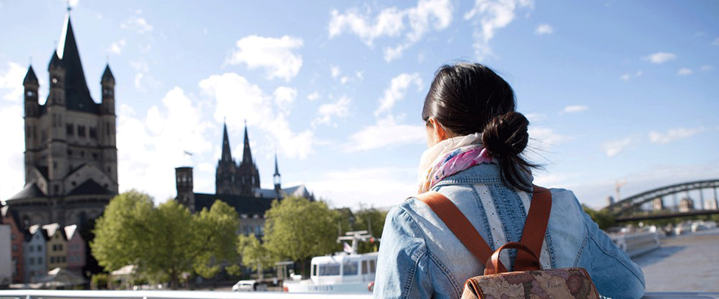 Eine Promovierende schaut von einer Brücke aus auf die Stadt Köln