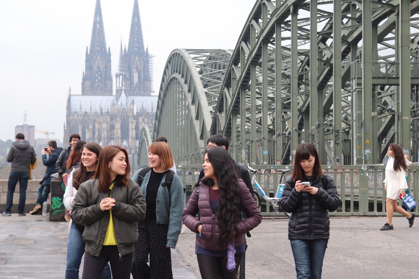 Few students in front of the Hohenzollern bridge with the cologne cathedral in the background.