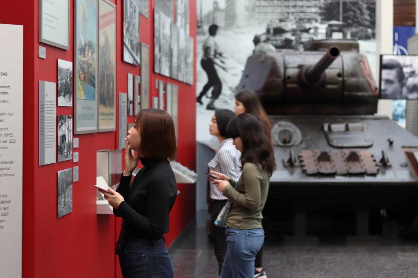 Students looking at the exhibits in the Haus der Geschichte. There is a tank in the background.