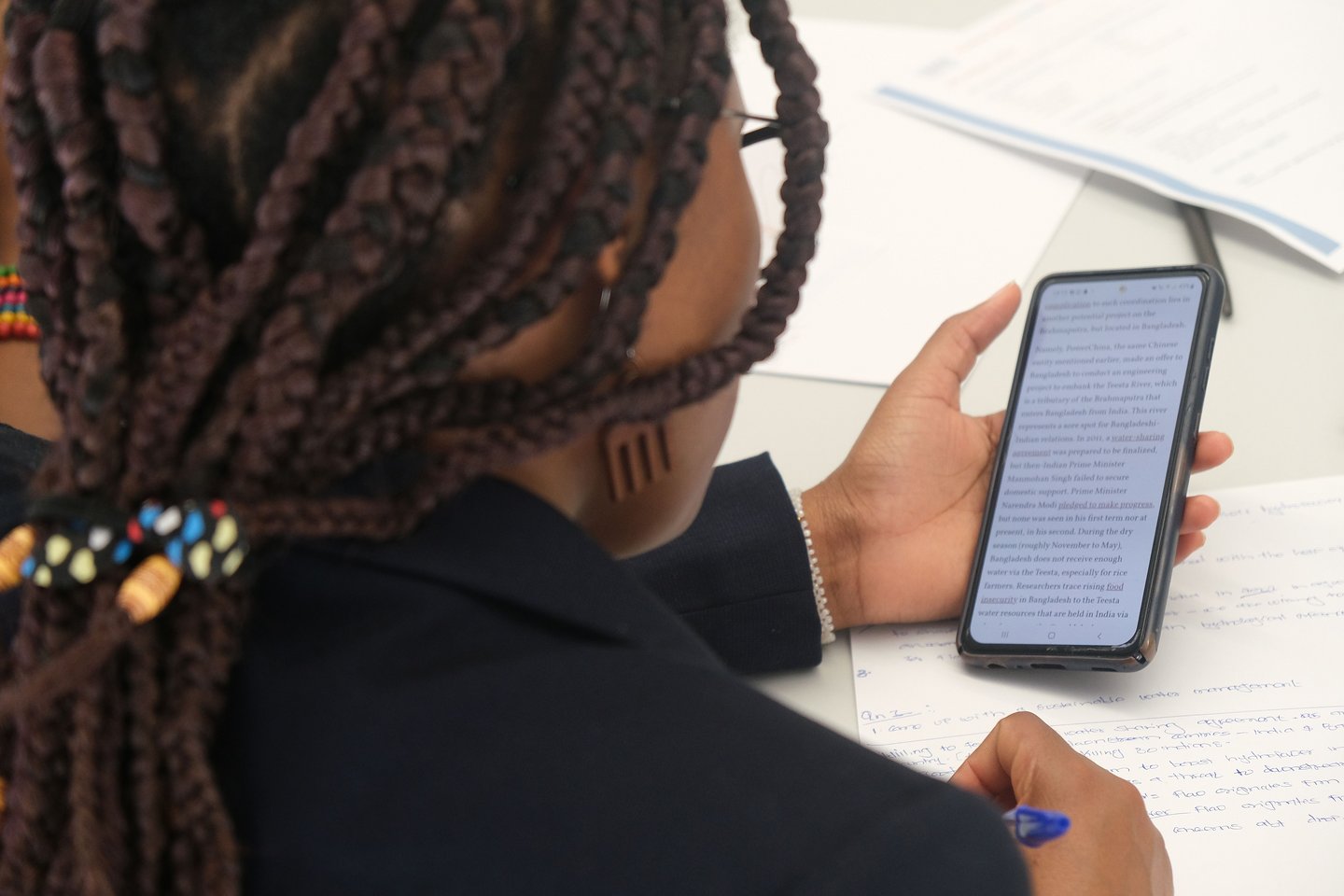 Afrikanische Studentin recherchiert auf ihrem Telefon, Daten zum Wasserverbrauch