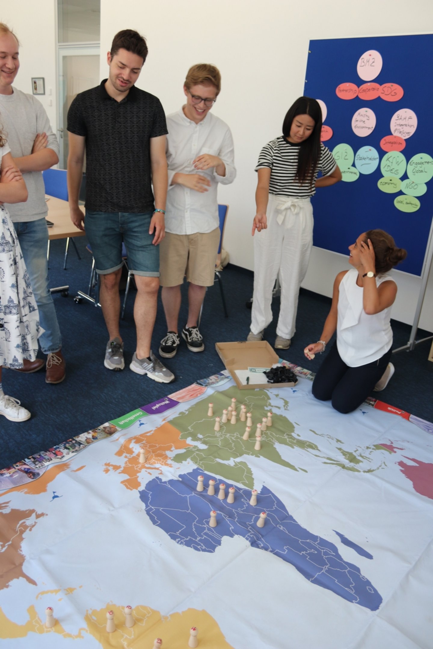 Students playing a game on a big worldmap on the floor.