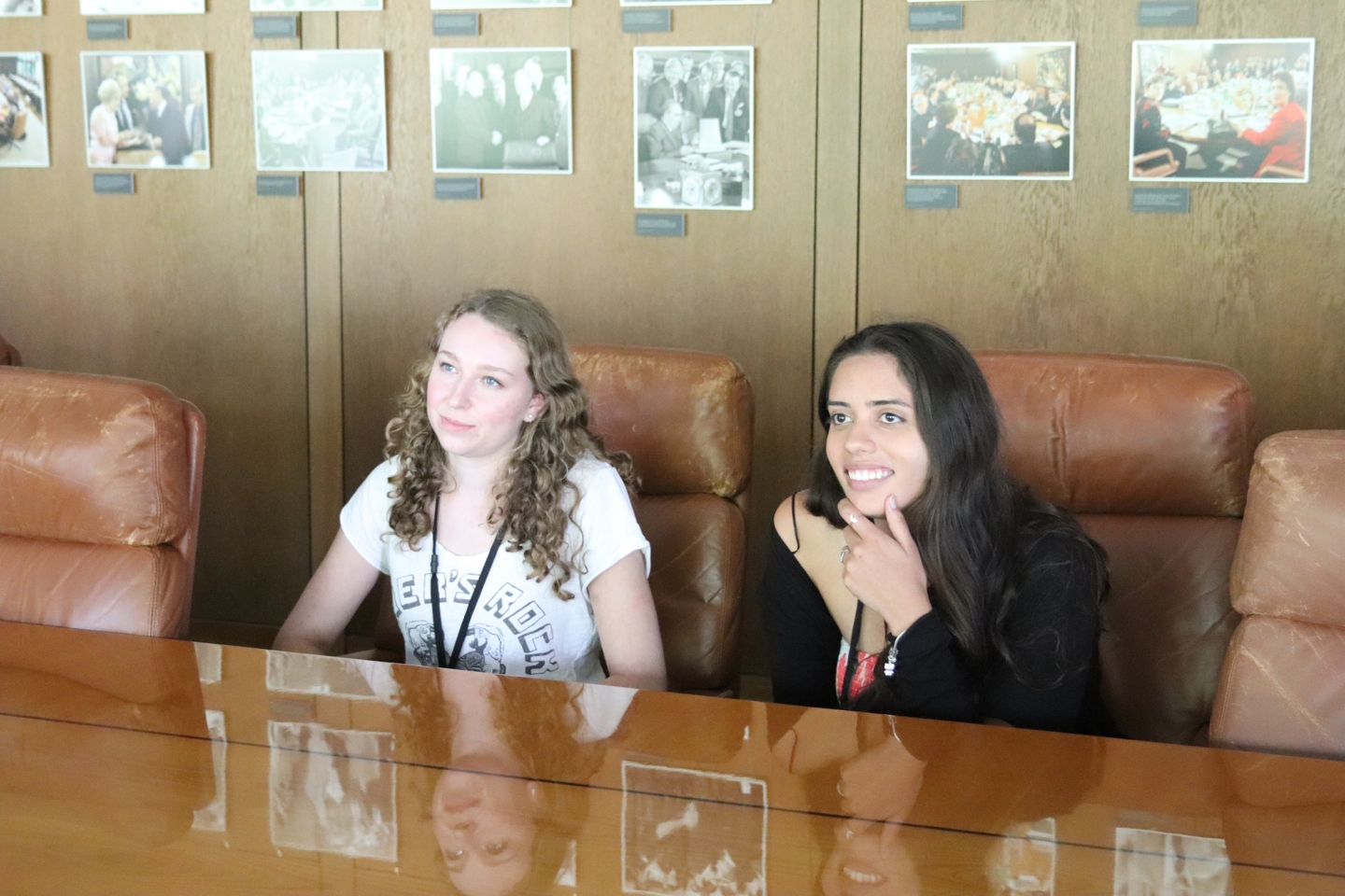 Two students sitting at a conference table in big leather chairs.
