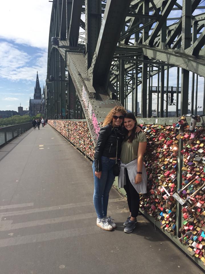 Two girls on the hohenzollern bridge in cologne. On the railing of the bridge are many locks.