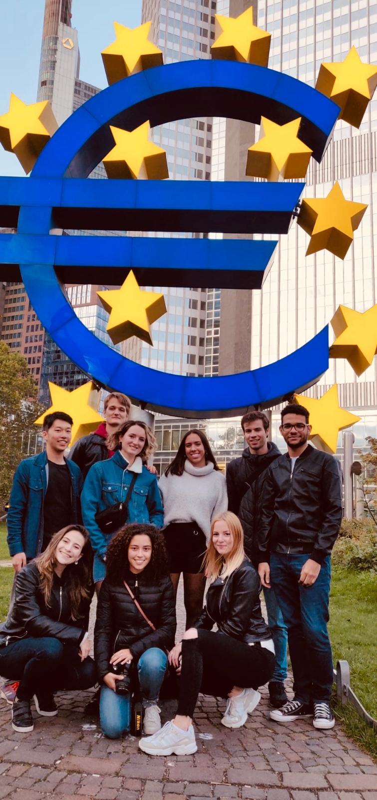Group of students in front of a euro sign with yellow stars in brussels.