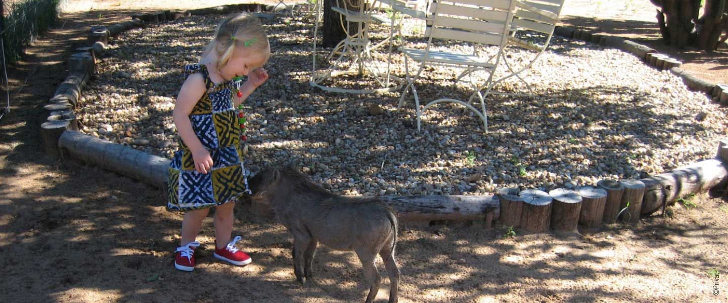 Silke Schroors Tochter spielt mit einem Tier unter einem Baum