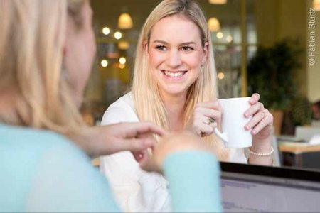 Zwei Frauen beim Kaffesetrinken, eine lächelt